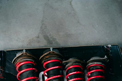 Four struts with red coil springs, worn ones beside new ones